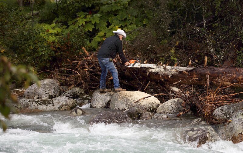 Marty Raney chopping up a log on the side of the river. – Bild: Warner Bros. Discovery, Inc. or its subsidiaries and affiliates