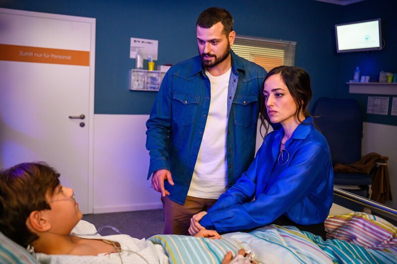 Nico Şahin (Caspar Boecken, l.) kämpft um sein Leben; seine Eltern Dr. Tarik Şahin (Nicolas Fethi Türksever, M.) und Elin Şahin (Céline Yildirim, r.) sind besorgt. – Bild: ZDF und Julia Feldhagen