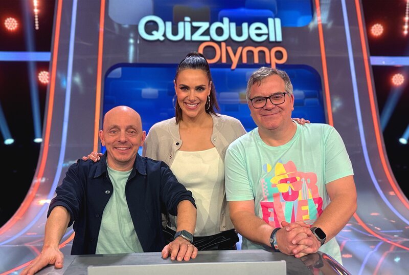 Moderatorin Esther Sedlaczek (M.) mit den Kandidaten des Teams „WWDS“: Bernhard Hoecker (l.) und Elton (r.). – Bild: ARD/​ITV Studios