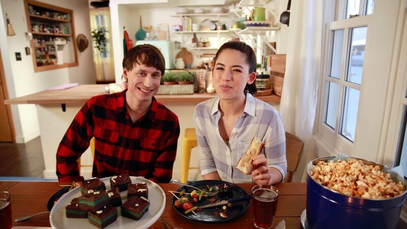 Candid shot of Molly Yeh and her husband Nick at dinner table with Sausage, Peppers, Onion Deep Dish Pizza, Mint Truffle Bars, Caramel Cheddar Popcorn, & Chicago Corn Dogs, as seen on Girl Meets Farm, Season 7. – Bild: Discovery, Inc. All Rights Reserved.