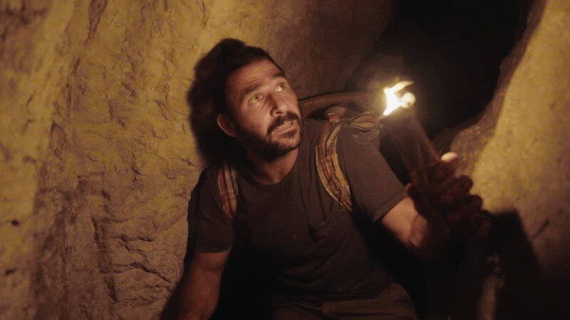 Hazen geht mit einer handgefertigten Fackel durch Tunnel in einer Höhle (National Geographic). – Bild: National Geographic