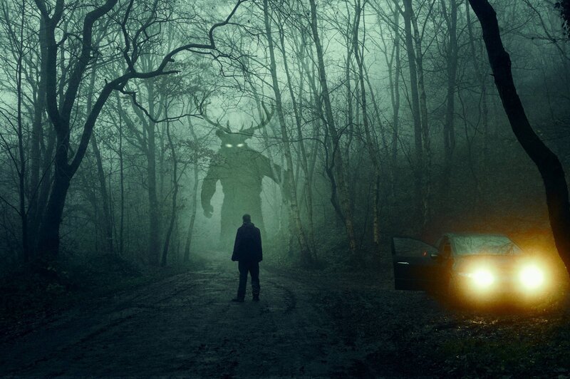 Ein Horror-Konzept. Ein Mann, der neben einem Auto steht und ein Monster mit glühenden Augen betrachtet. In einem gespenstischen, nächtlichen Winterwald Mit einer Grunge-Texturbearbeitung – Bild: Not Released (NR)/​David Wall