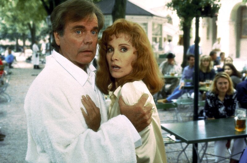 Kurz nach ihrer Ankunft in München wird Jennifer (Stefanie Powers, r.) auf offener Straße überfallen, doch ihr Mann Jonathan (Robert Wagner, l.) kann den Angreifer in letzter Sekunde vertreiben … – Bild: Sat.1 Gold