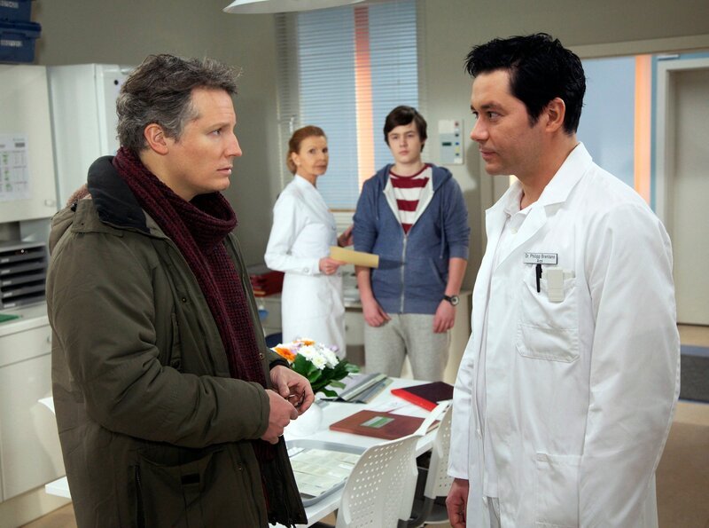 Marius Lechner (Leo Natalis Apitz, hinten rechts) wurde nach einer Sportverletzung an der Hand von seinem Vater und Sportlehrer Olaf Lechner (Max Urlacher, vorn links) in die Sachsenklinik gebracht. Als Dr. Philipp Brentano (Thomas Koch, vorn rechts) jedoch keine Verletzung feststellen kann, gesteht Marius, simuliert zu haben. – Bild: MDR/​Wernicke