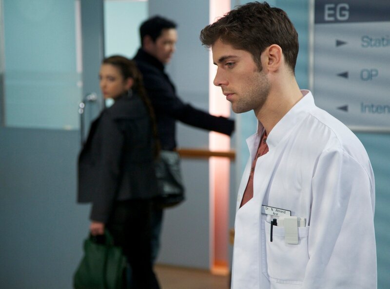 Dr. Niklas Ahrend (Roy Peter Link, vorn) leidet unter der Arzus (Arzu Bazman, hi. li.) Distanz. Seitdem sie miteinander geschlafen haben, macht sich Niklas noch größere Hoffnungen, sie für sich gewinnen zu können. Doch Arzu hat eine klare Entscheidung gefällt: Sie wird ihren Sohn und ihren Mann Dr. Philipp Brentano (Thomas Koch, hi. re.) nicht verlassen. – Bild: MDR/​Wernicke