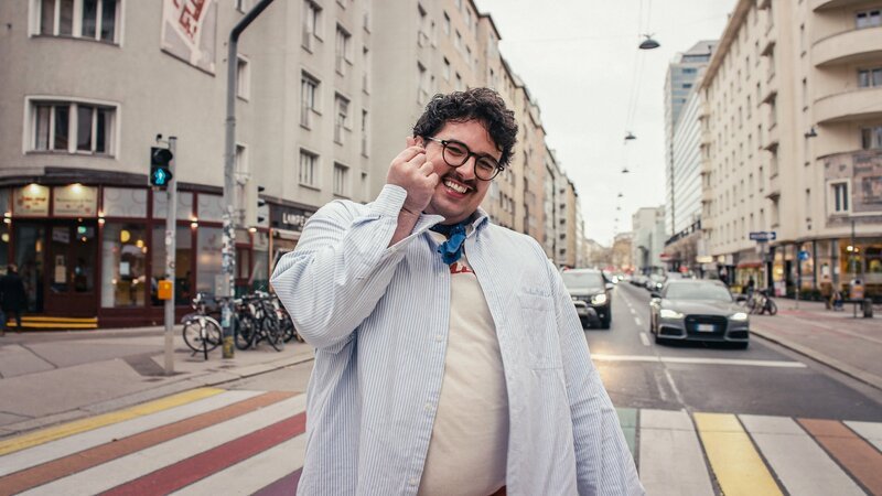 Matthias Gaeta posiert am Regenbogen Zebrastreifen. – Bild: ORF/​Neulandfilm