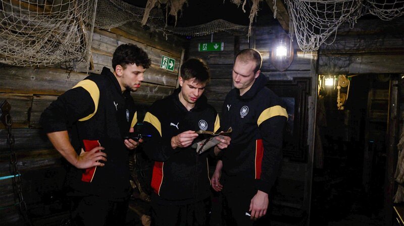 Renārs Uščins, Marko Grgić und David Späth lösen Aufgaben im Escape Room. – Bild: NDR