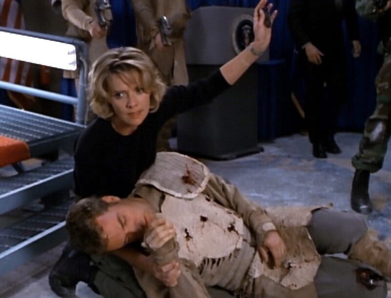 Nachdem Martouf (J.R. Bourne) erst auf den Präsidenten und dann auf sich selbst geschossen hat, stirbt er in Samanthas (Amanda Tapping) Armen. – Bild: RTL II