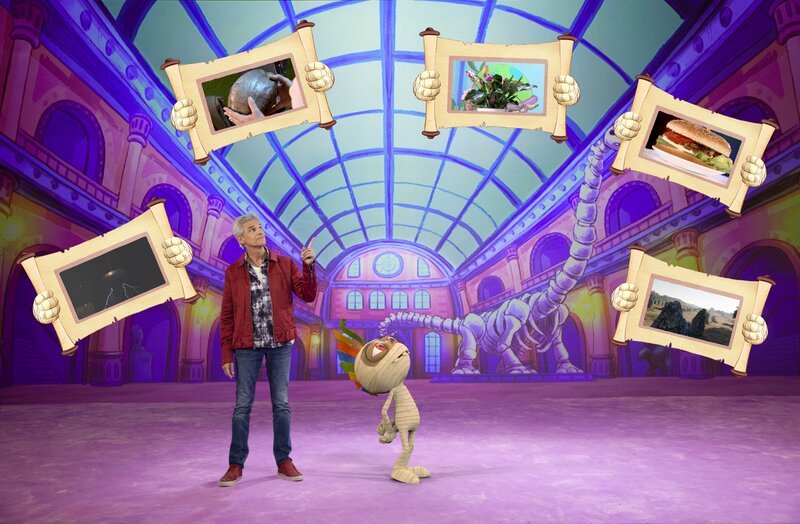 Thomas Brezina und Ramfetz mit den Gegenständen, deren Echtheit diesmal auf dem Prüfstand steht: Blitze machen Musik, Kokosnussbrief, Tropische Pflanze, die bei Musik wächst, Hamburger aus Insekten, Gebiss der Erde. – Bild: ORF