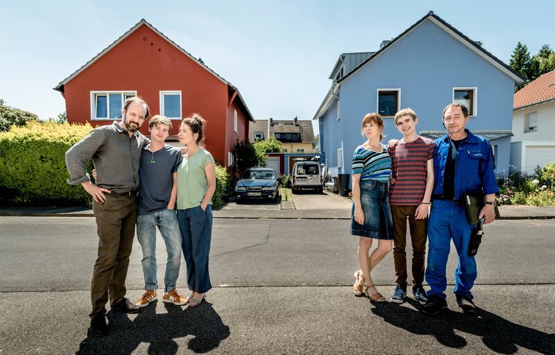 Christoph Schneider (Felix Knopp), David Schneider (Paul Sundheim) und Eva Schneider (Meike Droste) stehen vor ihrem roten Haus auf der Straße. Ulrike Pielcke (Milena Dreißig), Marvin Pielcke (Johannes Geller) und Frank Pielcke (Thorsten Merten) stehen nebeneinander vor ihrem blauen Haus. – Bild: Martin Rottenkolber /​ ZDF