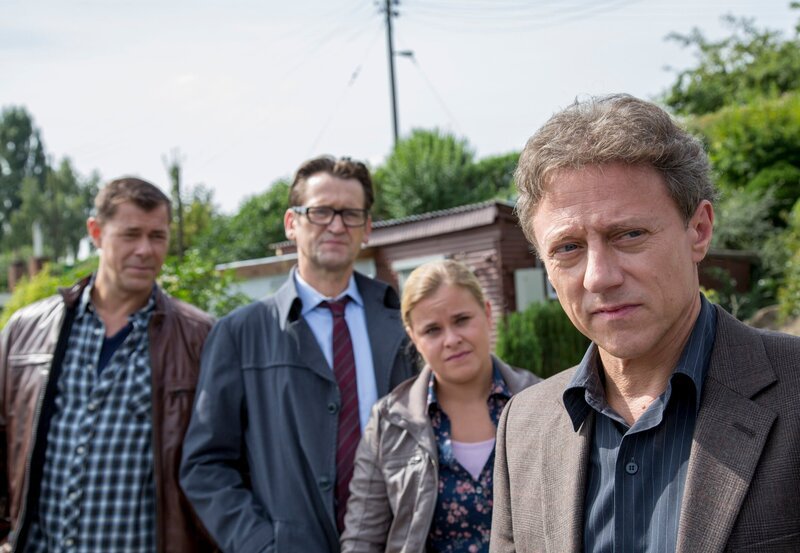 Am Ufer der Trave wurde eine tote Frau mit fehlendem Finger geborgen. Finn Kiesewetter (Sven Martinek, l.), Sandra Schwartenbeck (Marie-Luise Schram, 2.v.r.) und Lars Englen (Ingo Naujoks, 2.v.l..) rätseln über die Tatumstände. Hat Guido Olbrich (Axel Pape, r.) etwas damit zu tun? – Bild: NDR/​ARD/​Georges Pauly