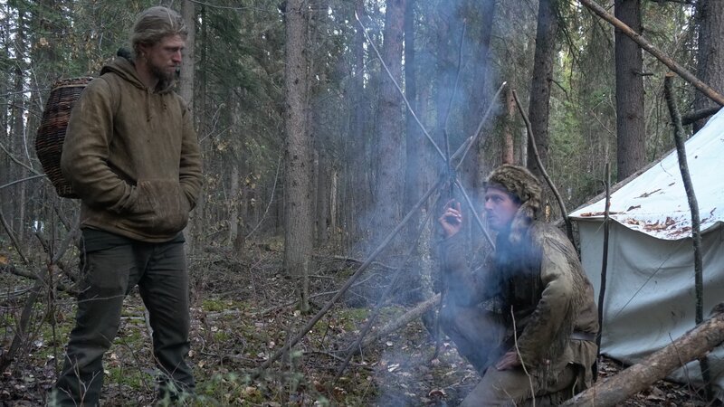 Oliver kneeling in front of wall tent, speaking to Gerrid. – Bild: Discovery Communications, LLC