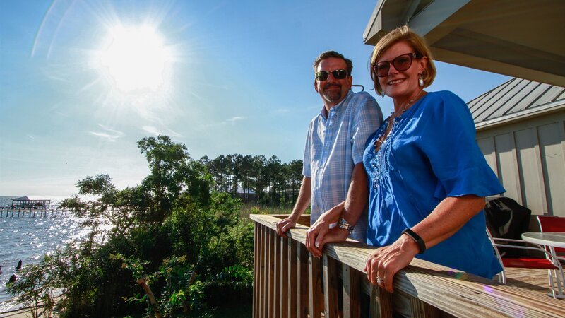 As seen on HGTV’s Beach Hunters, homebuyers Brent and Patrice pose for a photo while enjoying the views of Mobile Bay from the deck of the Wharf House in Fairhope, Alabama. – Bild: HGTV /​ Scripps (Focus);HBCHU201_275814_ /​ HGTV/​Scripps Networks, LLC