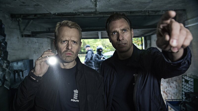 Zwei der Ermittler SP (Alexandre Willaume, r.) und Simon Clausen (Peder Thomas Pedersen, l.) kommen der Herkunft der benutzten Waffen auf die Spur. – Bild: ZDF/​Christian Geisnæs