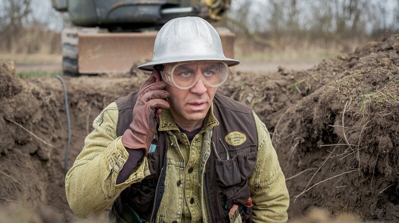 Mehmet Ösker (Cem Ali Gültekin) bringt mit seinem neu gegründeten Unternehmen, der ‚International Holding ÖS‘COMPANY Limited’, ganz Schwanitz durcheinander. – Bild: NDR/​Gordon Timpen