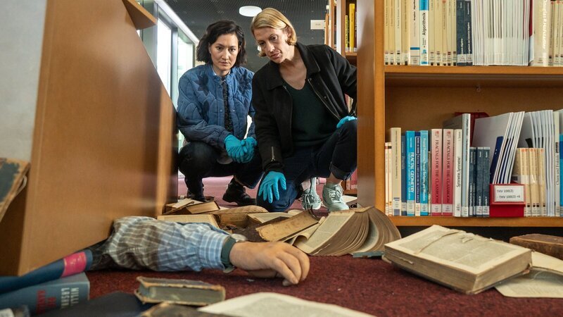 Pauline Hobrecht (Agnes Decker, l.) und Tamara Meurer (Anja Pahl, r.) kommen am Tatort an. Der Leiter der Hochschulbibliothek wurde unter einem Bücherregal begraben. Handelt es sich hier um einen tödlichen Unfall oder das letzte Kapitel einer buchreifen Mordintrige? – Bild: ZDF und BRITTA KREHL