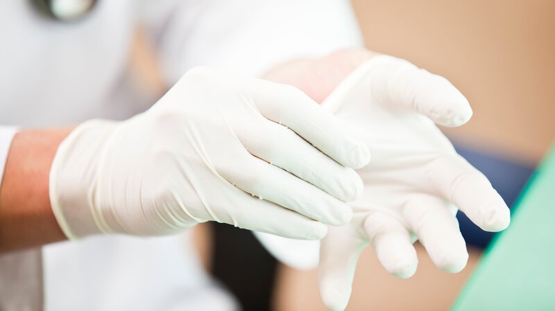 Doctor putting on examination gloves. Taken on iStockalypse Tokyo, Japan, 2010. – Bild: mbbirdy