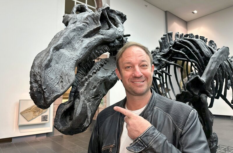 Moderator Tobis Kämmerer mit einem Dino im Senckenberg Museum in Frankfurt am Main. – Bild: HR/​Lukas Lowack