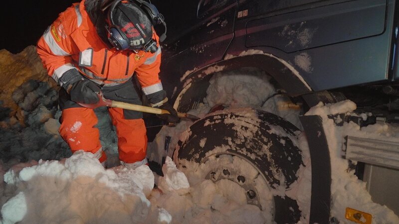Kaare schaufelt Schnee weg, der das Drehen der Räder verhindert. – Bild: National Geographic