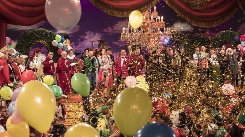 Reportage von den Vorbereitungen der Fastnacht, vom roten Teppich in Veitshöchheim, hinter den Kulissen der TV-Livesendung und von der After-Show-Party. Vorabbild aus 2018: Das große Finale mit allen Interpreten auf der Bühne. – Bild: BR/​Philipp Kimmelzwinger
