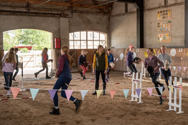 Hobby-Horse-Training auf dem Reiterhof. Bei der neumodischen Sportart wird Pferdesport mit Steckenpferden absolviert. Doch die heile Welt der jungen Hobby-Horserin Fine Hofmeister (Smilla Löhr, l.) droht schon bald, aus dem Sattel zu kippen. – Bild: ZDF und BRITTA KREHL