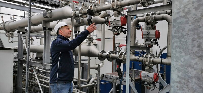 Experte für Wasserstofftechnik Markus Kainz bei den Anlagenröhren – Bild: ServusTV /​ Ferdinand Rubert