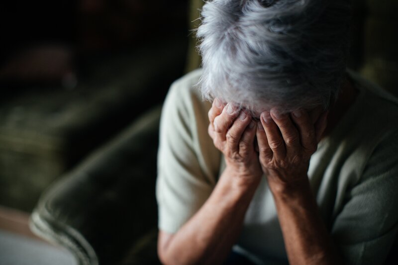 Eine Seniorin hält sich die Hände vors Gesicht. – Bild: BR/​Julia Müller