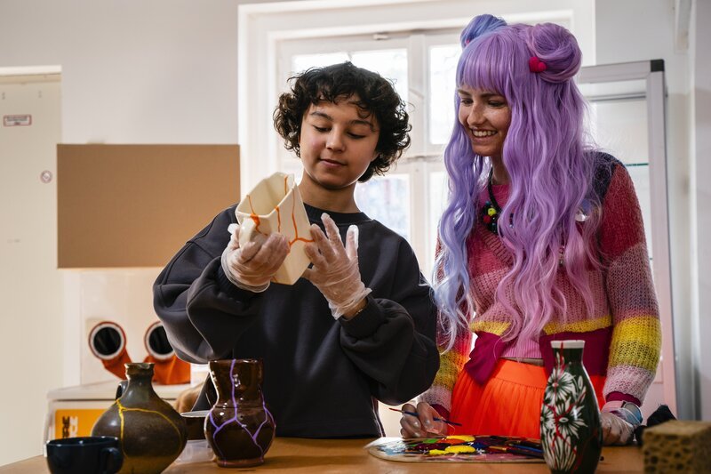 Tahmina (Janisa Glasow, li.) und Chiara (Jamila Kara Kichakuro Weintritt) kleben kaputtes Geschirr. Doch wie wollen sie damit den Share Space retten? – Bild: mdr/​Saxonia Media/​Thomas Dietze