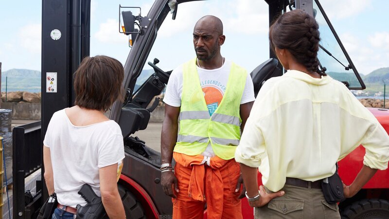 Als Verdächtiger in einem Mordfall wird der Hafenarbeiter Gaëtan Coste (Mark Grosy, M.) von den Kommissarinnen Gaëlle Crivelli (Béatrice De la Boulaye, l.) und Mélissa Sainte-Rose (Sonia Rolland, r.) befragt. Er hatte einige Tage vor dem Tod der ermordeten Frau Streit mit ihr. – Bild: ZDF und Matthieu Guitteaud – FTV