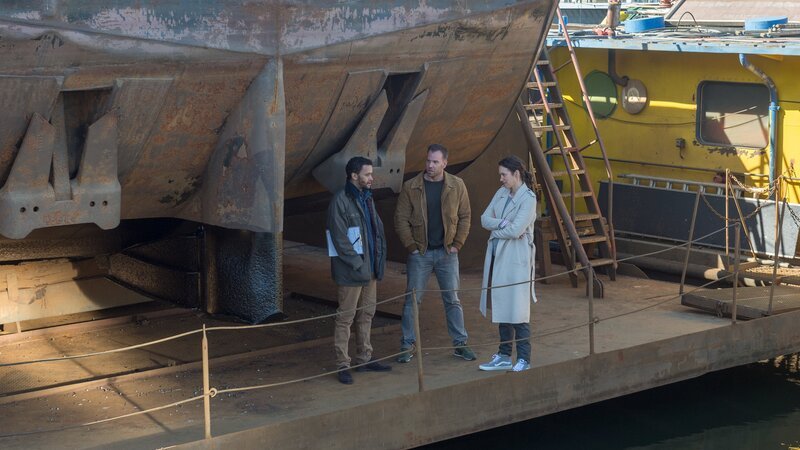 Karoline Joost (Nike Fuhrmann, r.) und Lars Pöhlmann (Dominic Boeer, M.) suchen den Freund der Toten, Thorsten Schröder (Thando Walbaum, l.), an seinem Arbeitsplatz in der Wismarer Werft auf. Er hat das Opfer auf ihrem Hausboot besuchen wollen, um ihr einen Heiratsantrag zu machen, und sie bereits tot vorgefunden. Doch war das Verhältnis zu seiner Partnerin wirklich so harmonisch, wie er vorgibt? Ein Mord aus Eifersucht scheint zumindest möglich. – Bild: ZDF /​ Meyerbroeker