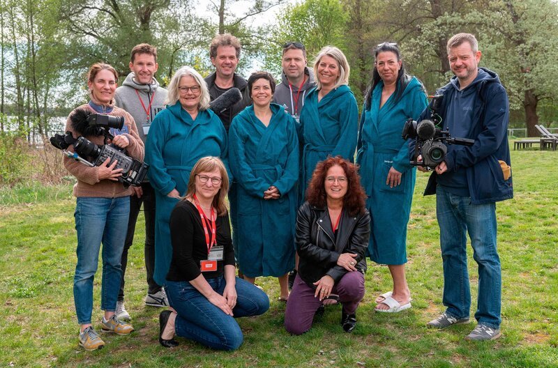 Hitzewallungen, Stimmungsschwankungen, Schlafstörungen – die Wechseljahre sind in der öffentlichen Wahrnehmung immer noch ein Tabuthema. Die neue dreiteilige Dokuserie „Die Frauensauna – Verdammte Wechseljahre!“ des Rundfunk Berlin-Brandenburg (rbb) begleitet vier Frauen über mehrere Monate in ihrem Alltag und bei intensiven, tabulosen Gesprächen in der Sauna. Das Team bei den Dreharbeiten. – Bild: mdr/​rbb/​Oliver Ziebe