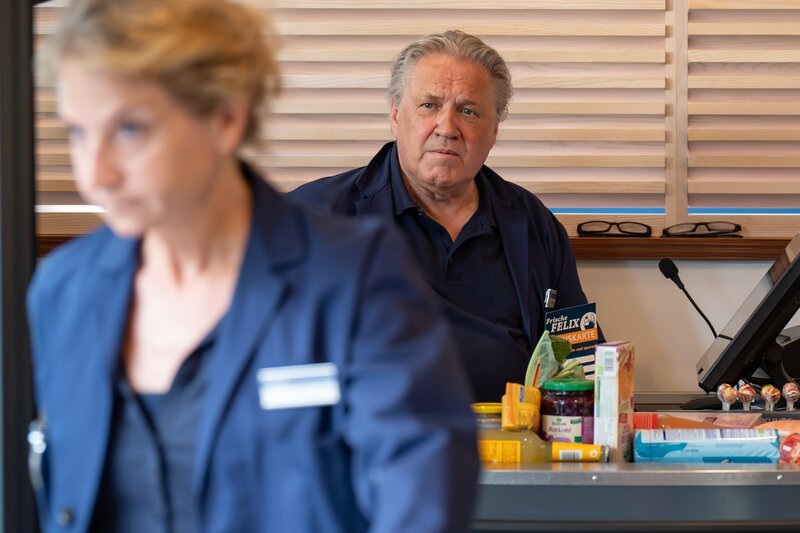 Girwidz (Michael Brandner, r.) „probt“ an der Kasse. Ist die Filialleitung (Natalie Hünig, l.)  etwa unzufrieden mit ihm? – Bild: Leonine/​Thomas Neumeier