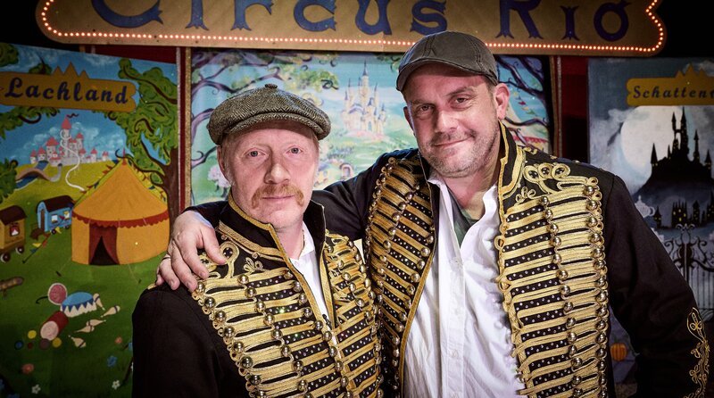 Die „Grenzgänger“ Sebastian Bezzel (rechts) und Simon Schwarz in der Zirkusmanege des Rio Artistik. – Bild: BR/​Film Five GmbH/​Bernd Schuller