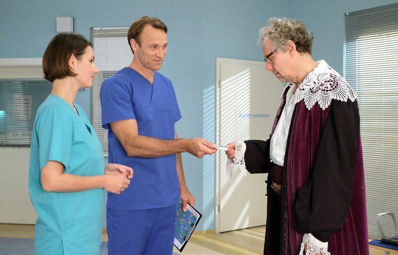 Der Enkel von Michael Pawletko (Thomas Bading, re.) hat bei seiner Ritter-Geburtstagsfeier etwas verschluckt. Dr. Martin Stein (Bernhard Bettermann, 2.v.li.) und Dr. Maria Weber (Annett Renneberg, li) haben den Fremdkörper entfernt. Als sie ihn Michael zeigen, staunen alle drei nicht schlecht. – Bild: MDR/​Saxonia Media/​Kiss