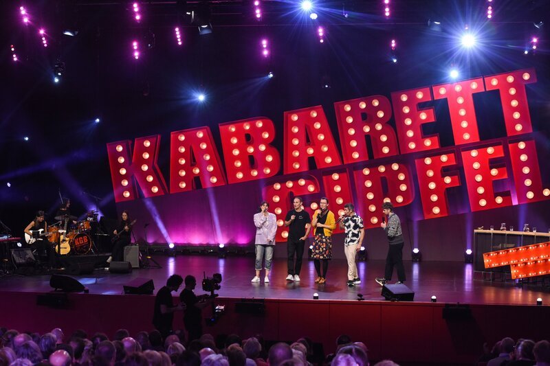 Eva Maria Marold, Gernot Kulis, Martina Schwarzmann, Omar Sarsam, Benedikt Mitmannsgruber (v.l.n.r.) und „Die Kabarettgipfelband“. – Bild: E&A Film /​ ORF /​ Hubert Mican