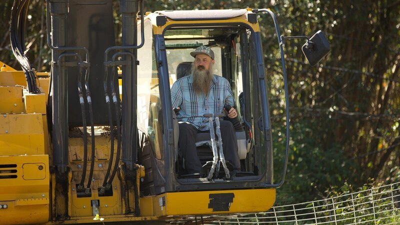 Matt Raney using the excavator to clear away invasive guava trees for the new livestock oasis. – Bild: Warner Bros. Discovery
