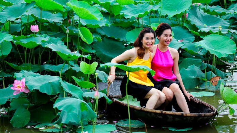 Der Westlake am Stadtrand von Hanoi war schon immer Anziehungspunkt, für Pärchen, die der Großstadt entfliehen wollten, für Picknick und Romanzen. Diese beiden Damen lassen sich inmitten des Blumenmeers fotografieren. – Bild: ZDF/​NDR/​Philipp Abresch