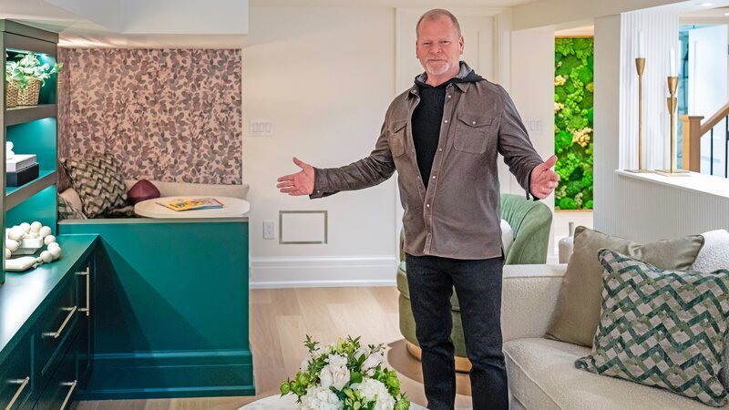 Mike showing off some of the new features of the new basement living room. – Bild: HGTV US /​ Restovate Ltd. /​ Discovery, Inc.