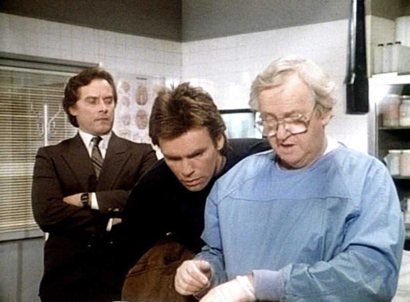 Bannister (Michael W. Goodwin, l.) und MacGyver (Richard Dean Anderson, M.) beobachten, wie der Pathologe (Arthur Malet, r.) eine Gewebeprobe entnimmt. – Bild: Kabel Eins Classics