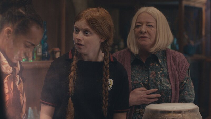 Mildred (Lydia Page, M.) und Frau Graustein (Clare Higgins, r.) wollen Indigo (Kelsey Calladine-Smith) helfen, dass sie ihr junges Äußeres wieder dauerhaft behält. – Bild: ZDF/​CBBC/​ZDF Enterprises