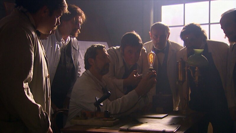 Thomas Alva Edison begutachtet eine Glühbirne. – Bild: ZDF/​Hans Jakobi