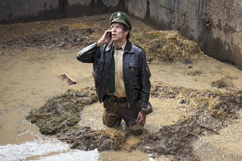 Staller (Helmfried von Lüttichau) ist bei dem Versuch eine Probe aus der Güllegrube zu entnehmen, in die Jauche gefallen. Über Handy versucht er Hubert zu erreichen, damit der ihn rausholt. – Bild: BR/​ARD/​TMG/​Chris Hirschhäuser