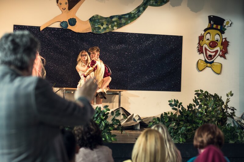 Deniz (Levin Alin, r.) und Frau Bischoff (Jeanne Goursaud, l.) vergnügen sich Backstage während einer Ballettaufführung, als plötzlich der Vorhang fällt. – Bild: ZDF und Efe Cetinoezman
