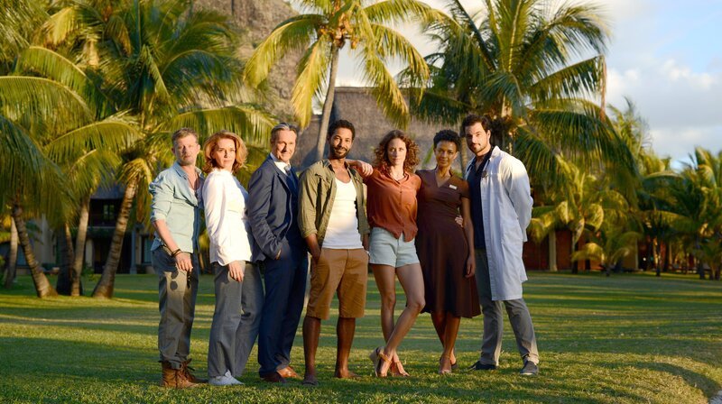 Von links nach rechts: Tom (Andreas Guenther), Küchenchefin Rachel (Valentina Sauca), Hoteldirektor Kulovits (Helmut Zierl), Barkeeper Mike (Tyron Ricketts, li.), Hotelärztin Filipa Wagner (Anja Knauer), Küchenmanagerin Emi (Dennenesch Zoudé) und Dr. Daniel Bucher (Tobias Licht). – Bild: ARD Degeto/​Tivoli Film/​Alexander Schumann