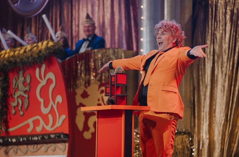 Ted Louis alias Peter Karl zeigt in seinem orangenen Anzug Falschspielertricks. – Bild: SWR/​Ronny Zimmermann