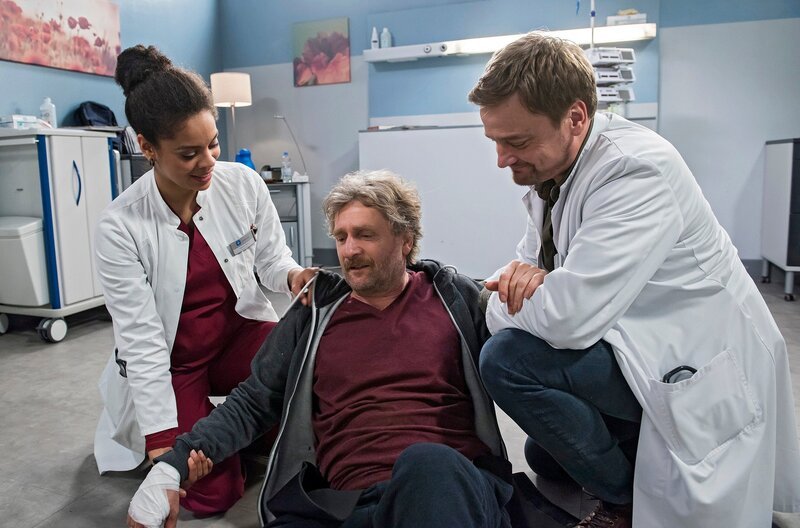 Kai Lenz (Jörg Witte, Mitte) bricht vor den Augen von Vivienne Kling (Jane Chirwa, links) und Dr. Marc Lindner (Christian Beermann, rechts) erschöpft zusammen. – Bild: ARD/​Jens Ulrich Koch