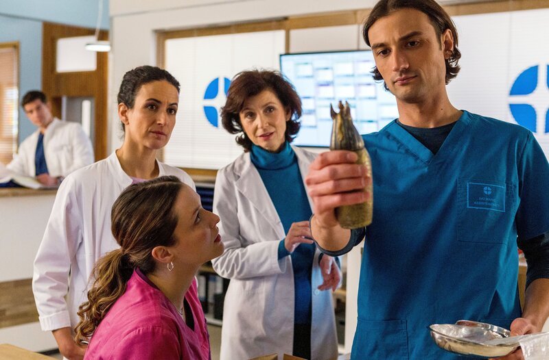 Die Ärztinnen Viktoria Stadler (Isabella Krieger, 3.v.l.), Leyla Sherbaz (Sanam Afrashteh, 2.v.l.) und Karin Patzelt (Marijam Agishewa, 2.v.r.) zeigen sich vom Aberglauben unbeeindruckt. Assistenzarzt Ivo Maric (Jakob D’Aprile, r.) soll das Objekt im Labor untersuchen (mit Philipp Danne, h.l.). – Bild: ARD/​Tom Fülle