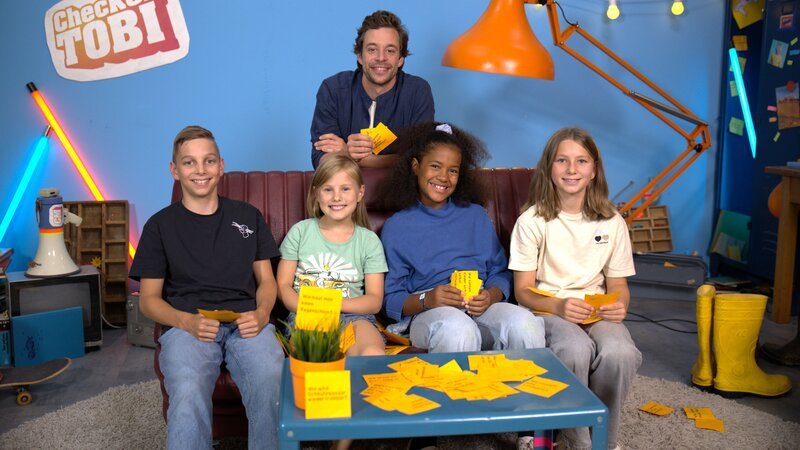 Tobi mit den Kindern aus dem Kinder-Check in der Checkerbude. – Bild: BR/​megaherz gmbh/​Hans-Florian Hopfner