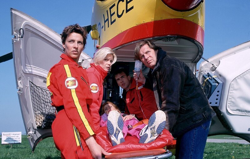 Pilotin Biggi (Sabine Petzl, li.), Notärztin Gabriele (Anja Freese, 2.v.li.), Sanitäter Ralf (Wolfgang Krewe) und Dr. Stefan Frank (Sigmar Solbach, re.) tragen Irene Kadenbach (Claudia Wenzel) in den Medicopter. – Bild: RTLplus /​ Elke Werner