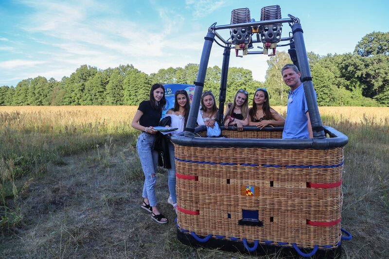 Von links: Toni, Anna, Luise, Alexa, Feli und Gert. Die Mädchen stehen zusammen mit Ballonpilot Gerd am Korb des Ballons. Gleich steigen sie zusammen 1000 Meter hoch in die Luft. – Bild: e+u TV /​ ZDF